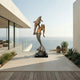 Monumental Classical Mermaid and Dolphin Bronze Sculpture by Giant Sculptures, gilded finish, displayed on an oceanfront terrace with succulents and glass railing.