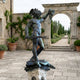 Giant Sculptures Monumental Classical Perseus and Medusa Bronze Sculpture in dark verdigris patina on a carved stone plinth in a stone courtyard.