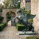 Monumental Classical Rearing Pegasus Bronze Sculpture by Giant Sculptures with verdigris patina, rearing beside a stone manor's arched garden gateway.