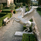Giant Sculptures' 300cm Monumental Classical Rearing Pegasus Bronze Sculpture in a pale silver-white finish, displayed on a paved garden path beside clipped hedges.