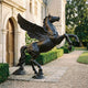 Monumental Classical Rearing Winged Horse Bronze Sculpture by Giant Sculptures in deep black patina, displayed on a stone walkway beside a château entrance.