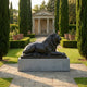 Monumental Classical Recumbent Lion Bronze Sculpture by Giant Sculptures on a grey granite plinth, set on a stone path between cypress trees facing a classical pavilion.