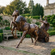 Monumental Classical Roman Chariot with Warrior and Horses Bronze Sculpture by Giant Sculptures, reddish-brown patina, rearing horses in a walled garden setting.