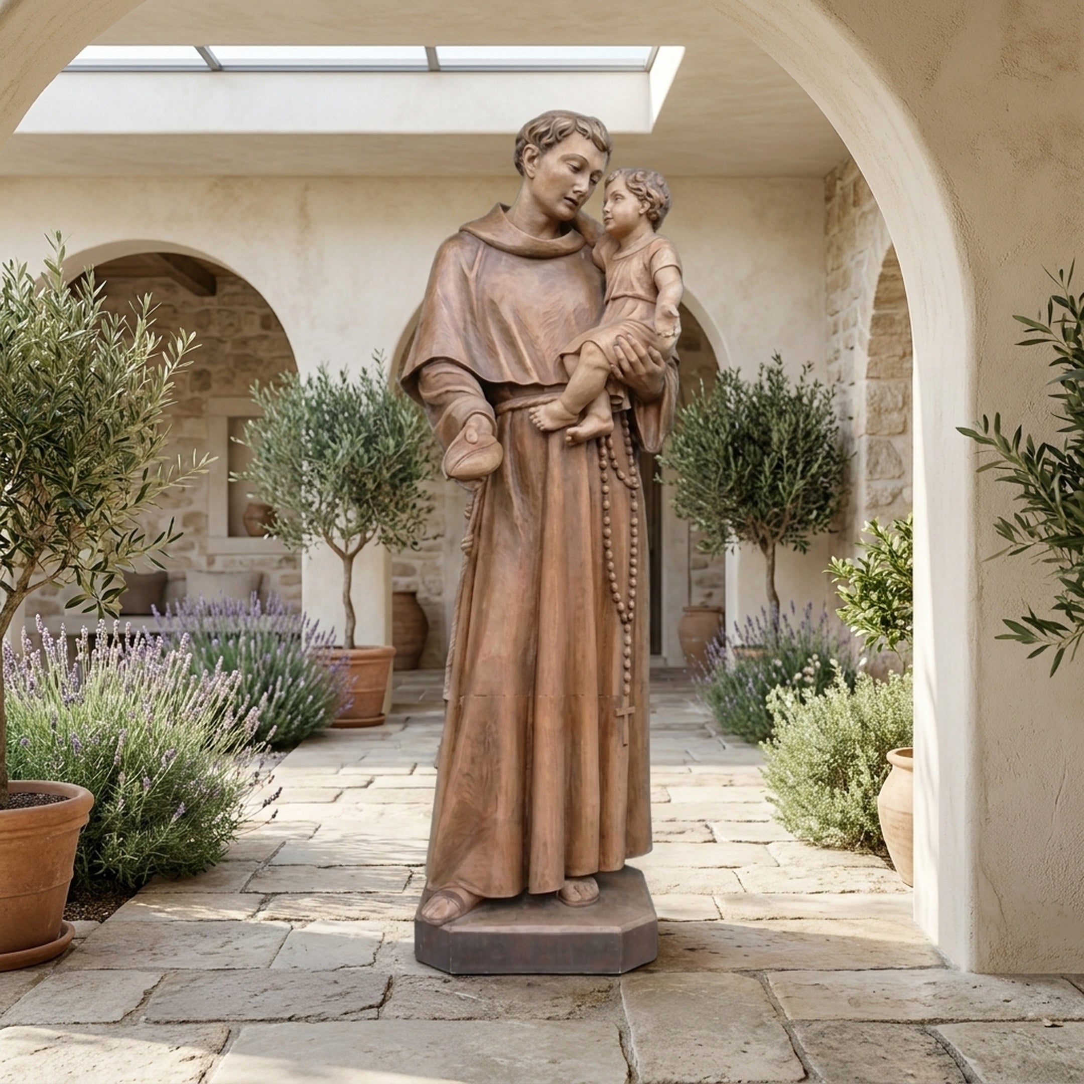 Monumental Classical Saint Anthony and Christ Child Bronze Sculpture by Giant Sculptures displayed in a Mediterranean courtyard with olive trees and lavender.
