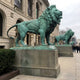 Monumental Classical Standing Lion Bronze Sculpture by Giant Sculptures, verdigris patina, shown in profile on stone pedestal flanking a classical building entrance.