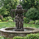 Monumental Classical Three Figures Bronze Fountain by Giant Sculptures, 280cm, with draped female figures supporting a two-tier basin with lion-head spouts in a garden.