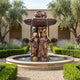 Monumental Classical Three Figures Fountain in bronze by Giant Sculptures, with draped caryatids, lion-head spouts and fluted basin in a lavender courtyard garden.