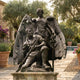Giant Sculptures Monumental Classical Victory Angel and Wounded Soldier Bronze Sculpture on a stone plinth in a Mediterranean garden beside olive trees and a pool.