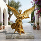 Monumental Classical Winged Angel Bronze Sculpture in gilded gold by Giant Sculptures, wings outstretched on a stone plinth beside a Mediterranean poolside terrace.