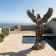 Giant Sculptures Monumental Classical Winged Angel Bronze Sculpture 300cm with raised torch and spread wings, set beside a reflecting pool overlooking the ocean.