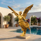 Monumental Classical Winged Victory Angel Bronze Sculpture in polished gold finish by Giant Sculptures, displayed beside a pool in a white-arched courtyard.