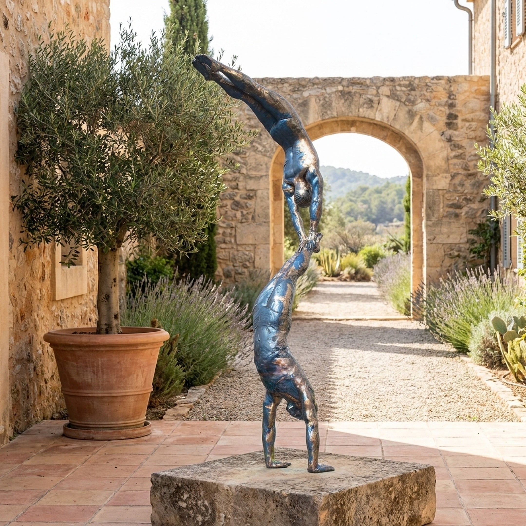 Monumental Contemporary Acrobatic Figures Bronze Sculpture by Giant Sculptures, two patinated bronze acrobats stacked in handstands on a stone plinth in a Mediterranean courtyard.