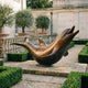 Giant Sculptures Monumental Contemporary Arched Dolphin Bronze Sculpture 200cm with warm brown patina, arched on a stone plinth in a formal garden with olive trees.