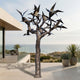 Monumental Contemporary Bird and Tree Bronze Sculpture by Giant Sculptures on a seaside terrace, with angular birds in flight across a textured branching trunk.