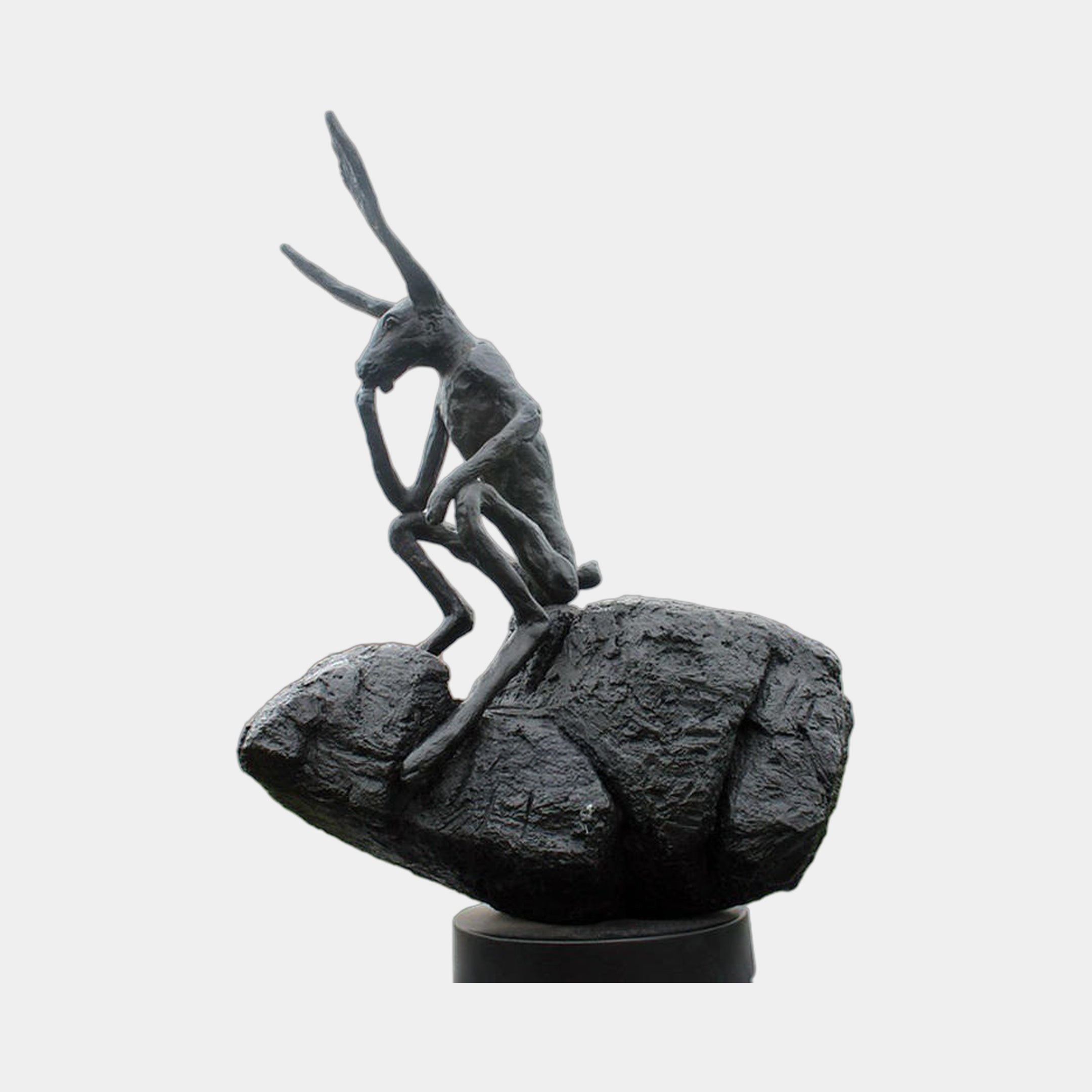 Giant Sculptures' Monumental Contemporary Contemplative Hare Bronze Sculpture in dark patina, seated atop a textured boulder in a reflective pose, on a plain background.