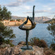 Giant Sculptures' 330cm Monumental Contemporary Dancer Bronze Sculpture in verdigris and gold finish, posed in arabesque on a rocky coastal outcrop overlooking the sea.