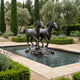 Monumental Contemporary Galloping Horses Bronze Fountain by Giant Sculptures, two dark patinated horses mid-stride on a rock base in a Mediterranean garden pool.