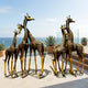 Monumental Herd of Six Giraffes Bronze Sculpture by Giant Sculptures, arranged in two groups of three on steel bases on a seaside terrace with potted agaves.