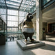 Monumental Contemporary Hippopotamus Ballerina Bronze Sculpture by Giant Sculptures displayed on a low plinth in a sunlit glass-walled atrium.