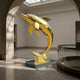 Monumental Contemporary Leaping Dolphin Bronze Sculpture by Giant Sculptures in mirror-polished gold, low-poly faceted form on a dark plinth in a museum hall.