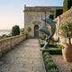 Monumental Contemporary Leaping Dolphins Bronze Sculpture by Giant Sculptures, verdigris and teal patina, displayed on a stone terrace overlooking the sea.