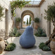 Monumental Contemporary Pear Fruit Bronze Sculpture by Giant Sculptures with dark blue-grey patina, displayed in a Mediterranean courtyard with olive trees.