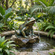 Giant Sculptures Monumental Contemporary Seated Frog Fountain bronze sculpture with verdigris patina, water cascading from its open mouth into a pond in a tropical garden.