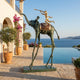 Monumental Surrealist Elephant and Trumpeting Rider Bronze Sculpture by Giant Sculptures on stilt-like legs beside an infinity pool overlooking the sea.