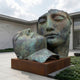 Monumental Contemporary Two Faces Bronze Sculpture by Giant Sculptures, 180cm, verdigris patina, on a corten-steel plinth in a paved courtyard.