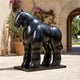 Monumental Contemporary Voluminous Standing Horse Bronze Sculpture in glossy black, displayed on a stone courtyard beside bougainvillea and an archway.