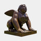 Monumental Contemporary Winged Female Sphinx Bronze Sculpture by Giant Sculptures, crouched with wings fanned and head lifted, warm brown patina, on a plain background.