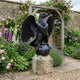 Monumental Heraldic Eagle Bronze Sculpture by Giant Sculptures with wings spread, perched on an orb atop a stone plinth in a rose-filled garden.
