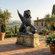 Monumental Heraldic Winged Lion Bronze Sculpture by Giant Sculptures, 220cm, seated with paw on sphere, on a stone plinth on a Tuscan villa terrace.