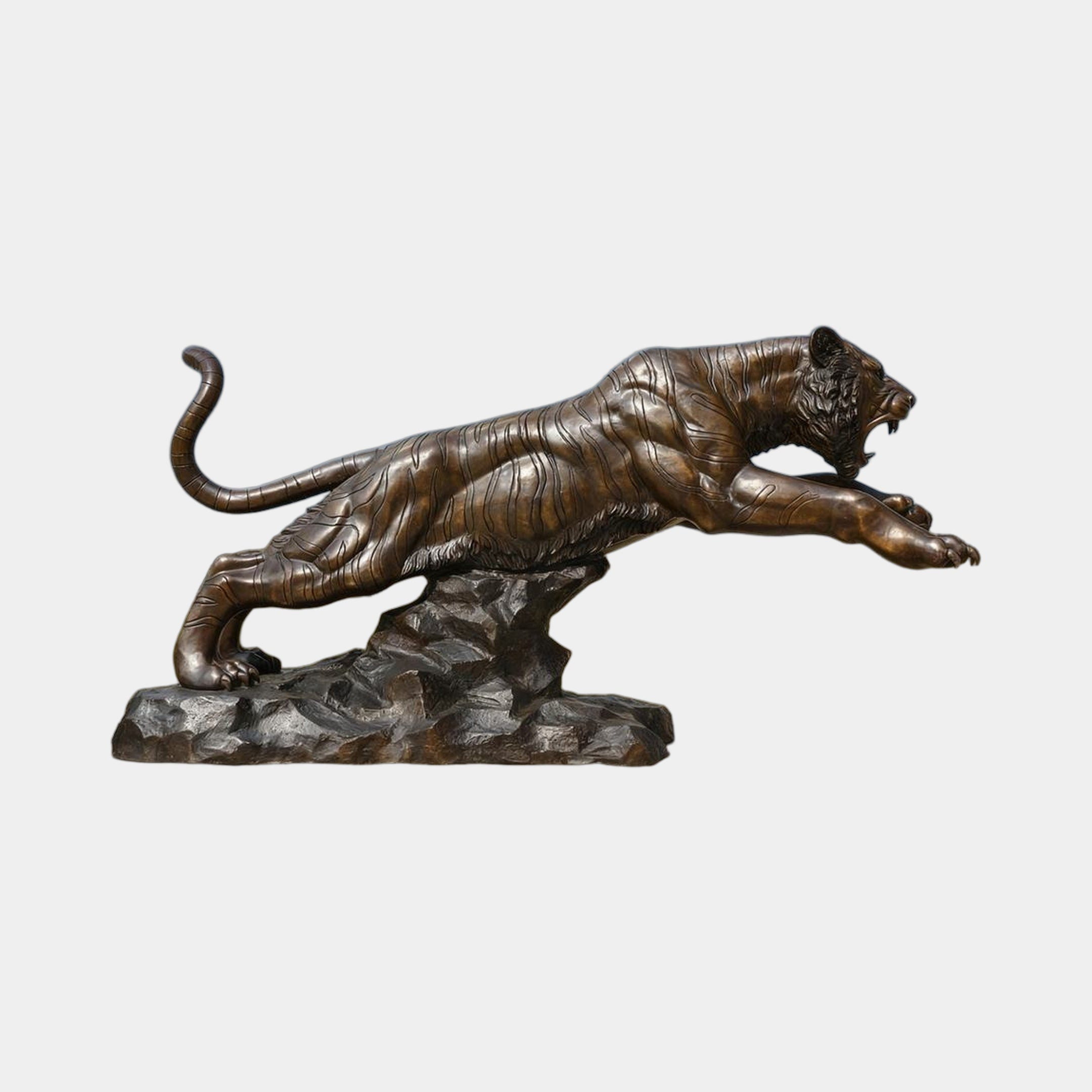 Monumental Life-Size Leaping Tiger Bronze Sculpture by Giant Sculptures, shown mid-lunge with bared fangs and extended claws on a rocky base, plain background.