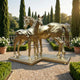 Monumental Mare and Foal Bronze Sculpture by Giant Sculptures in polished gold, two horses on a shared plinth in a cypress-lined formal garden.
