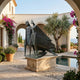 Giant Sculptures Monumental Modern Abstract Geometric Figures Bronze Sculpture with dark verdigris patina on a stone plinth in an arched Mediterranean courtyard.