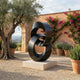 Monumental Modern Interlocking Ribbon Form Bronze Sculpture by Giant Sculptures on a pale stone plinth in a Mediterranean courtyard with olive tree and bougainvillea.