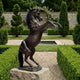 Monumental Rearing Horse Bronze Sculpture by Giant Sculptures with dark brown patina, mounted on a stone plinth in a formal garden with hedges and topiary.