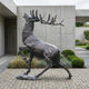 Monumental Rearing Stag Bronze Sculpture by Giant Sculptures shown side-on rearing on hind legs with antlers raised, displayed on paving beside a concrete wall.