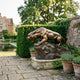 Monumental Roaring Panther Bronze Sculpture by Giant Sculptures, crouched mid-roar on a rocky base with golden-brown patina, displayed on a garden terrace.