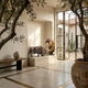 Monumental Traditional Charging Bull and Rearing Bear Bronze Sculpture Set displayed on a stone plinth in a sunlit Mediterranean entryway with olive trees.