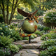 Monumental Traditional Eagle Globe and Anchor Bronze Sculpture by Giant Sculptures, green and gold patina, displayed on a stone path in a flowering garden.