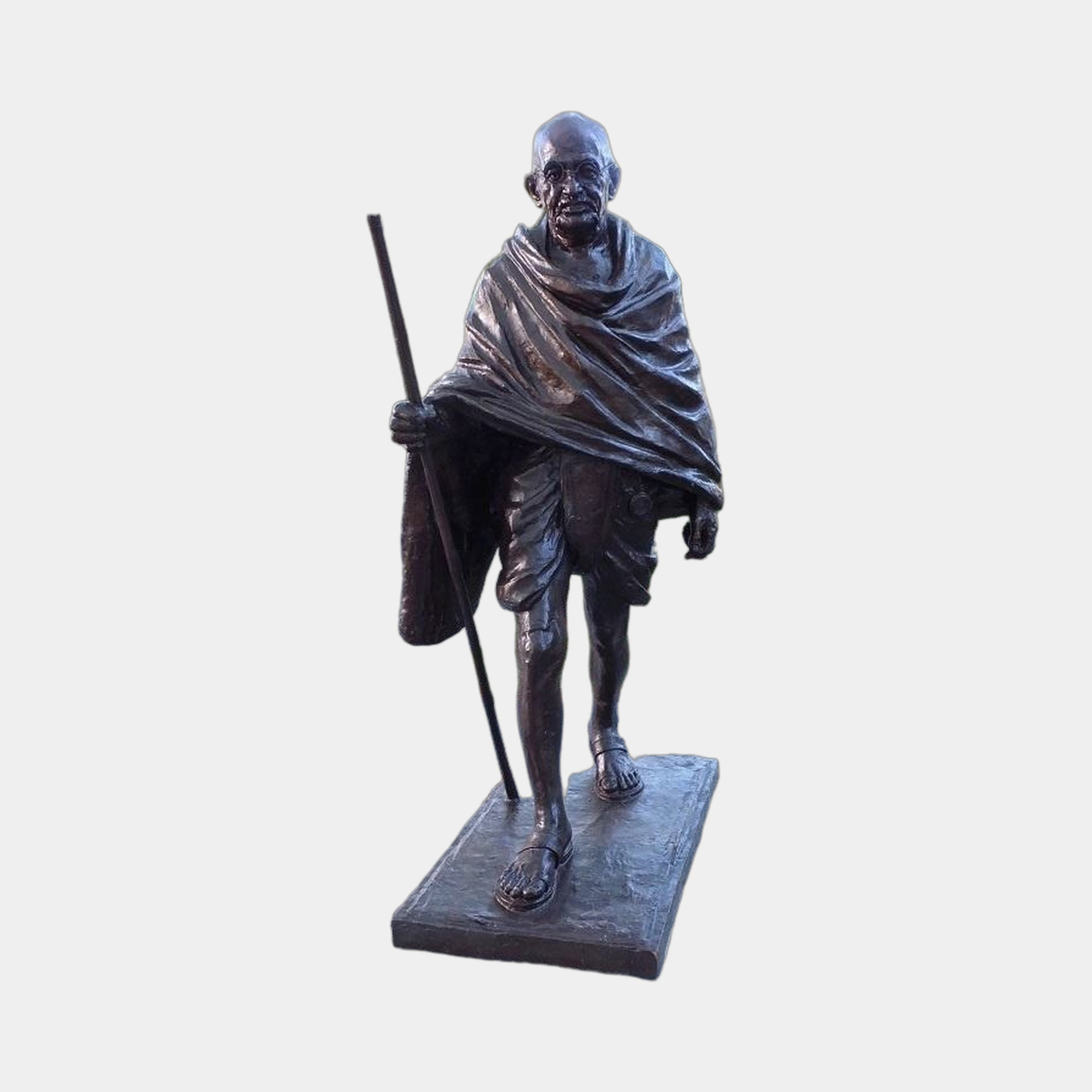 Monumental Traditional Elder Walking Figure Bronze Statue by Giant Sculptures, 230cm, shown mid-stride with staff and draped shawl in dark patina on a plain background.