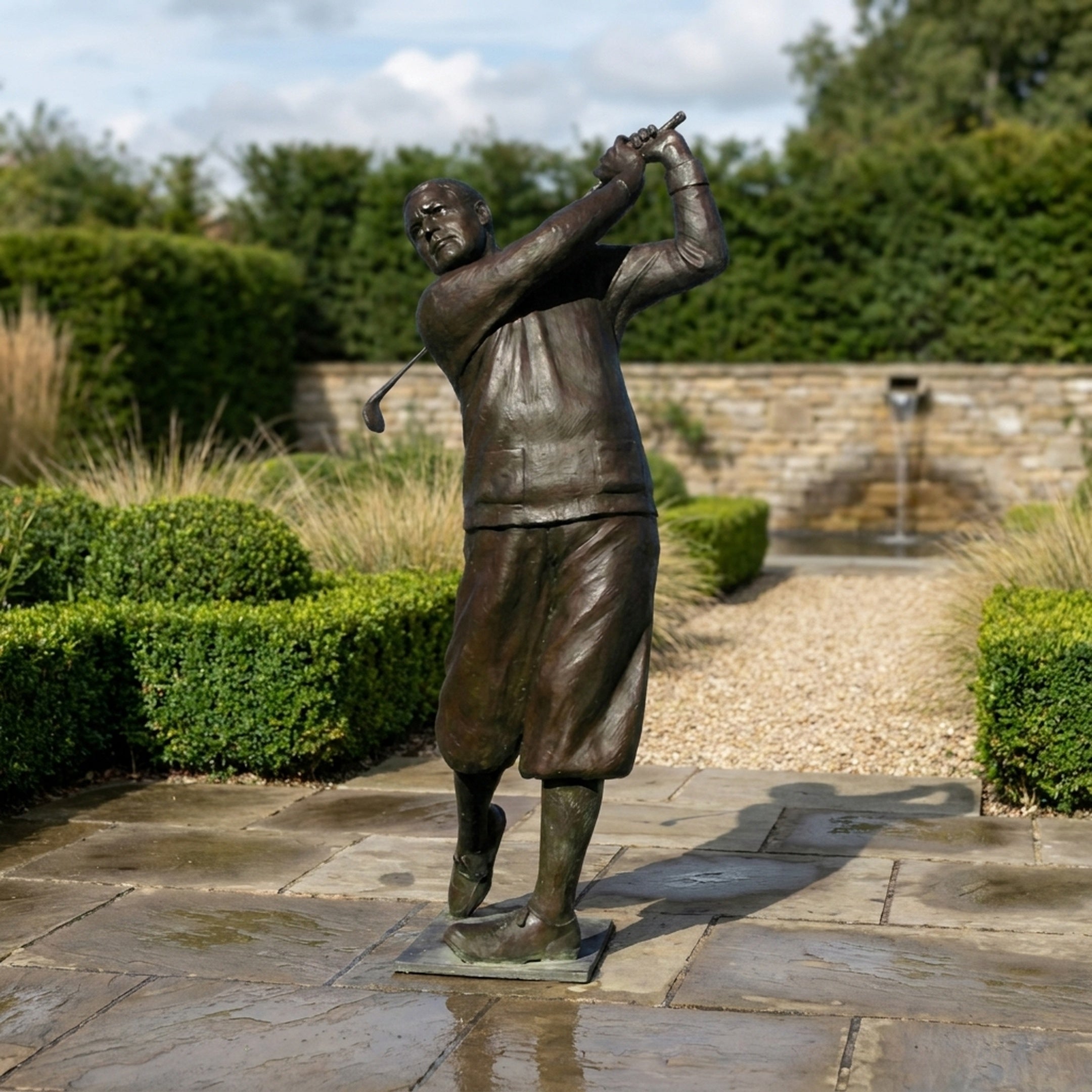 Monumental Traditional Golfer Bronze Sculpture by Giant Sculptures shown at follow-through with raised club and dark brown patina, displayed on a garden patio.