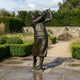 Monumental Traditional Golfer Bronze Sculpture by Giant Sculptures shown at follow-through with raised club and dark brown patina, displayed on a garden patio.
