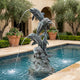 Monumental Traditional Leaping Dolphins Bronze Fountain by Giant Sculptures with verdigris patina, water arcing from four dolphins into a poolside setting.