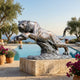 Giant Sculptures Monumental Leaping Tiger Bronze Sculpture 300cm on a stone plinth beside an infinity pool, with olive trees and sea view behind.