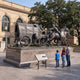 Monumental Traditional Pioneer Covered Wagon with Horse Team Bronze Sculpture by Giant Sculptures on a granite plinth with a family viewing the interpretive plaque.