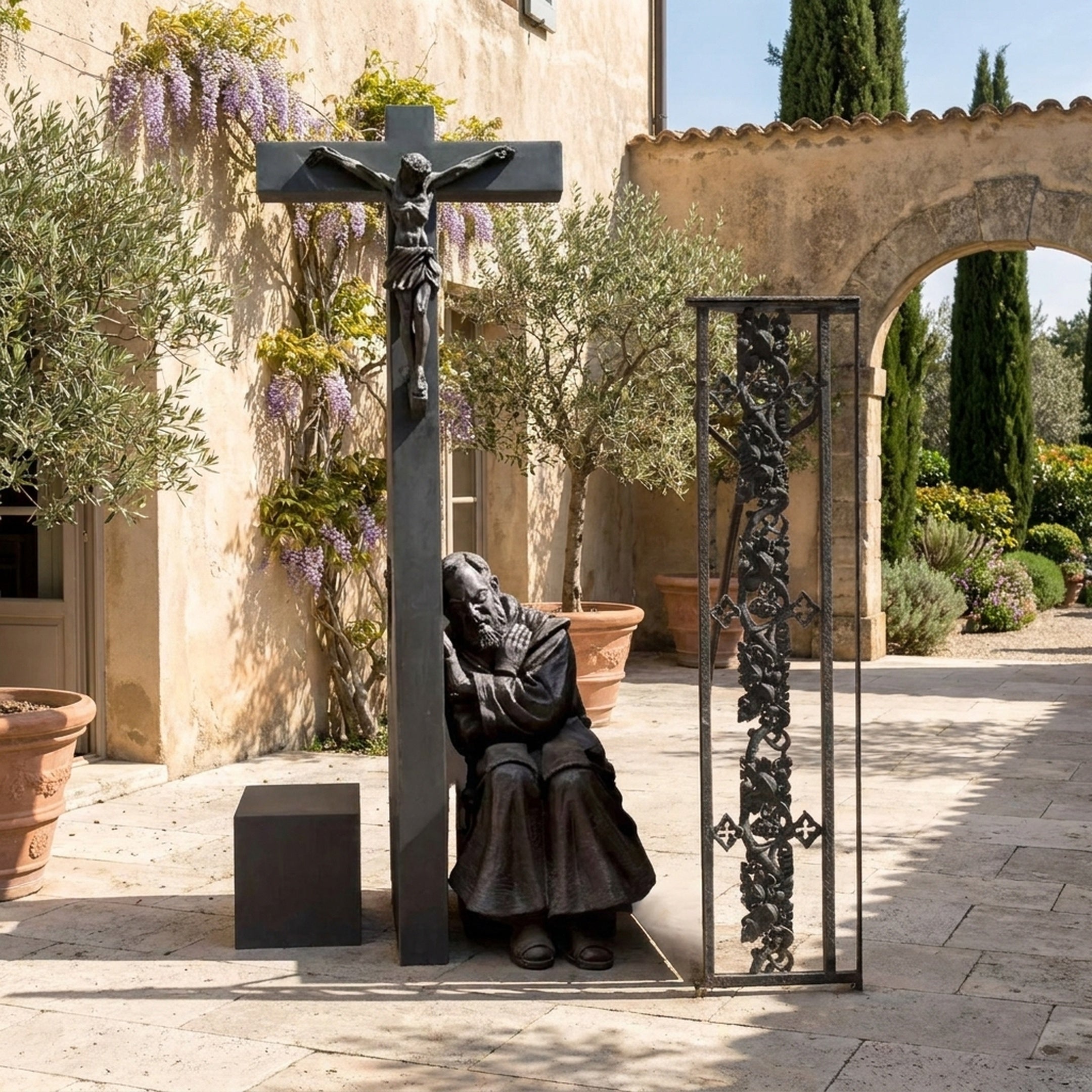 Monumental Traditional Praying Saint and Crucifix Bronze Sculpture by Giant Sculptures in a Mediterranean courtyard with wisteria, olive trees, and a stone arch.