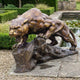 Giant Sculptures Monumental Traditional Prowling Panther Bronze Sculpture in golden-brown patina, crouched snarling on a rocky base beside a garden lily pond.